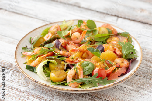 salad with shrimps and assorted salads (arugula, cherry tomatoes, chard, spinach) on white wooden background