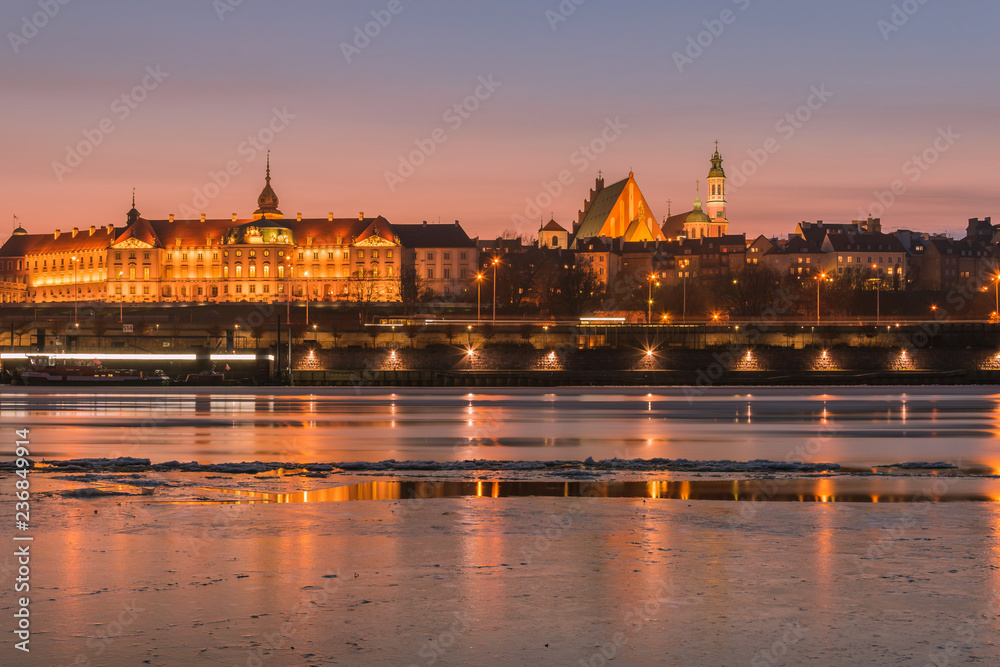 Warsaw skyline with  the Royal Castle and the Old Town buildings on the Vistula River shore by night. 