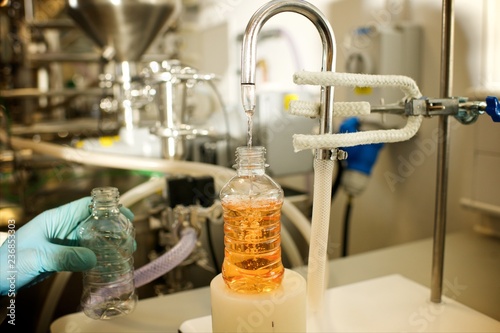Close up of a Lab technician using an industrial carbonator machine with an orange sugar drink