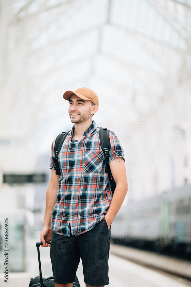 Traveler is late at the train station. Young man with backpack and suitcase missed the train and waiting for next. Traveler is late at the train station. Young man with backpack and suitcase missed the train and waiting for next.