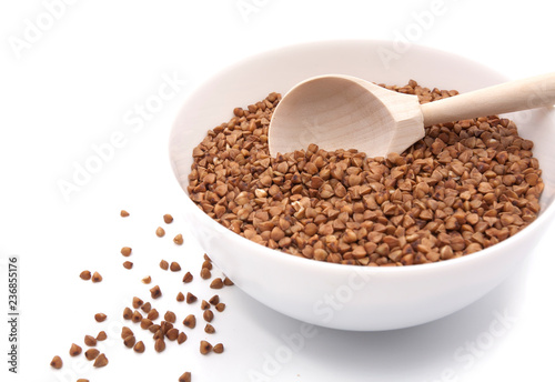 Buckwheat in a white bowl with a spoon. Isolated on white background.