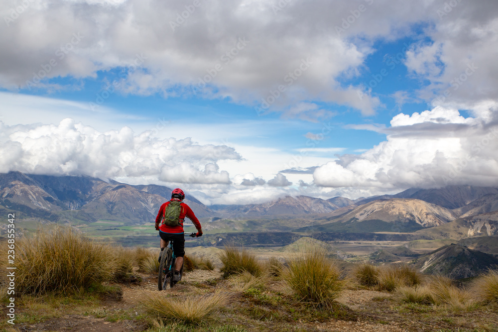 A mountain biker rides along the ridge and descends with beautiful landscape below