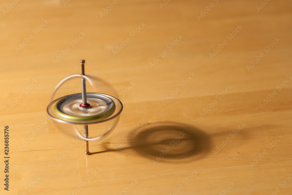 Toy gyroscope spinning and balancing on a wooden table Toy gyroscope spinning and balancing on a wooden table