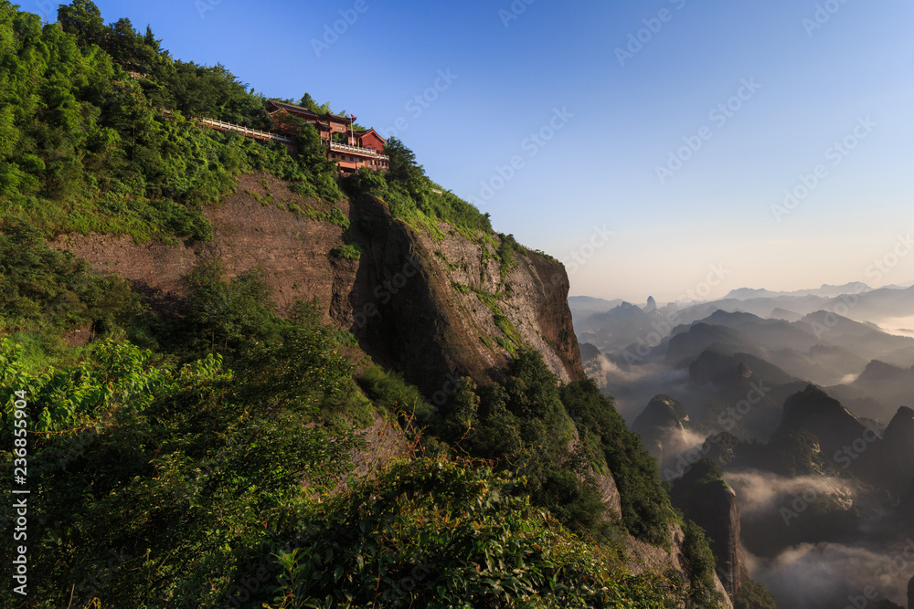 Bajiaozhai National Forest Park in Ziyuan County, Hunan Province China. Danxia landform, Longtouxiang Scenic Area. UNESCO World Heritage Site. View of Chinese Temple, overlooking Danxia Valley below.