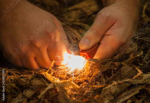 A pair of hands making a fire with flint and steel