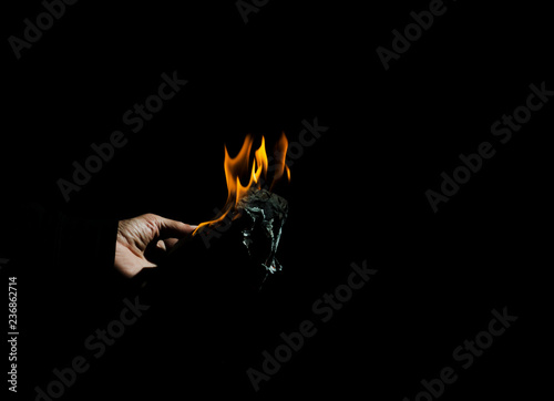 Burning sheet of paper in the male hand.