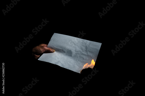 Burning sheet of paper in the male hand.