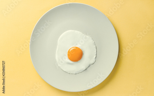 Fried egg tray on yellow background - Simple composition of egg on plate