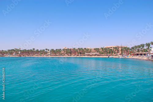 Tropical resort in Egypt. People swimming in sea. Tourists relax on beach