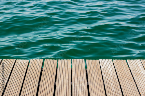 wooden desk waterfront pier floor and fuzzy sea vivid blue and green water background texture, copy space © Артём Князь