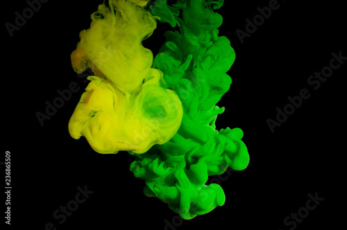 Spill and mix green and yellow paint in water on a black background