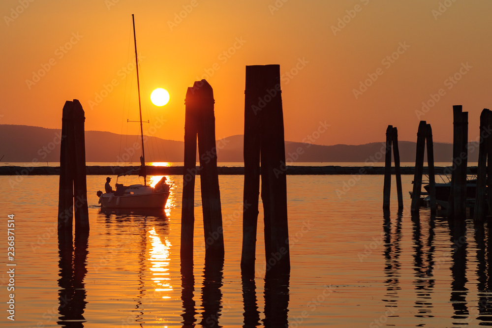 Sunset behind the mountains of Vermont with a silhouetted sailboat in foreground