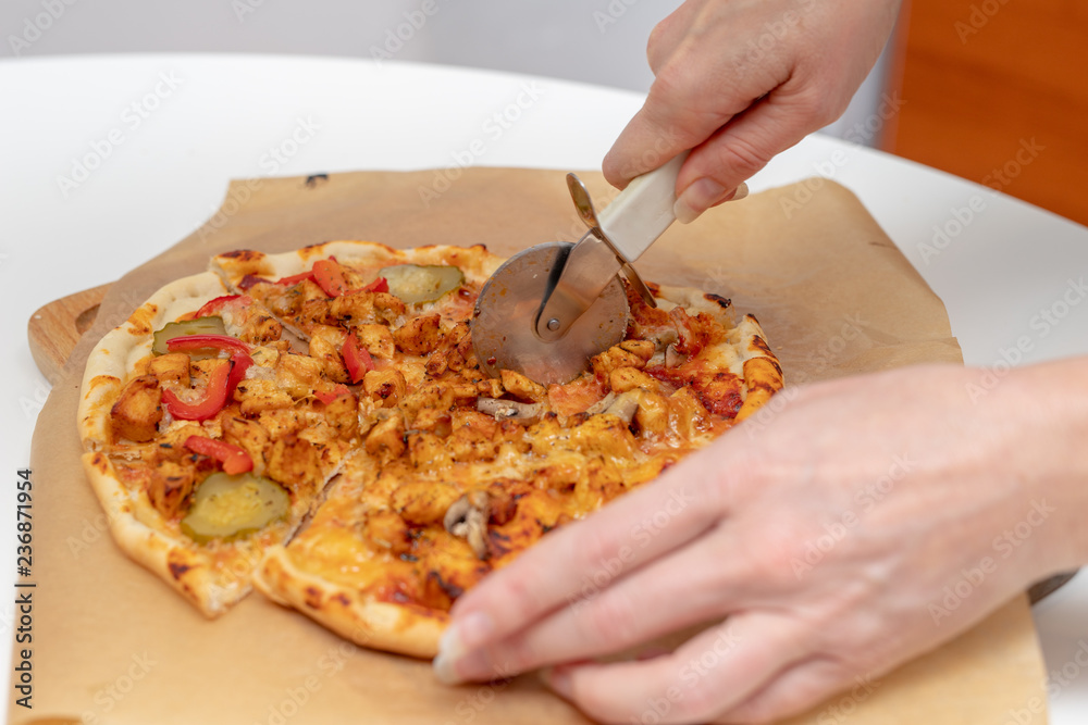Baking a delicious pizza in a home kitchen. Slicing and stacking the baked pizza on the kitchen table. Baking a delicious pizza in a home kitchen. Slicing and stacking the baked pizza on the kitchen table.