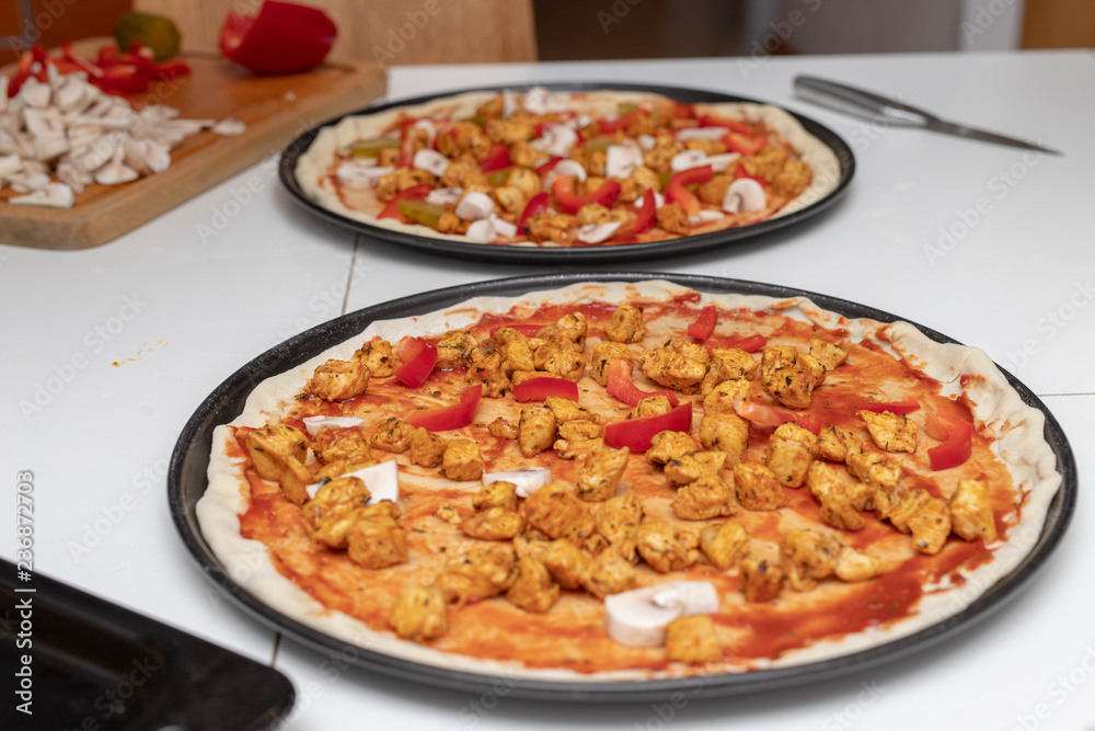 Preparation of a delicious pizza in a home kitchen. Laying and decorating pizza dough on the kitchen table. Preparation of a delicious pizza in a home kitchen. Laying and decorating pizza dough on the kitchen table.