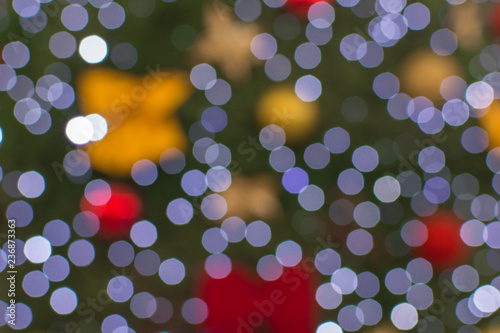 blurred background of christmas tree decorated with lights, balls, bows and gifts