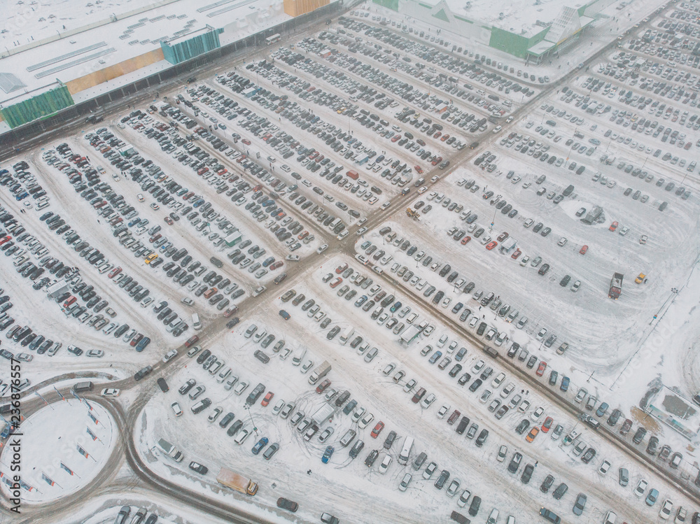 Aerial view of large automobile parking lot with many cars near mall or shopping center in winter with snow, drone photo Aerial view of large automobile parking lot with many cars near mall or shopping center in winter with snow, drone photo
