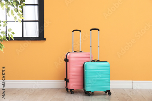 Suitcases packed for travel on floor near color wall