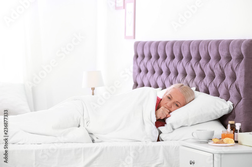 Ill mature woman suffering from cough in bed