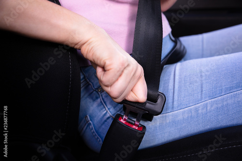 Woman Fastening Seat Belt In Car