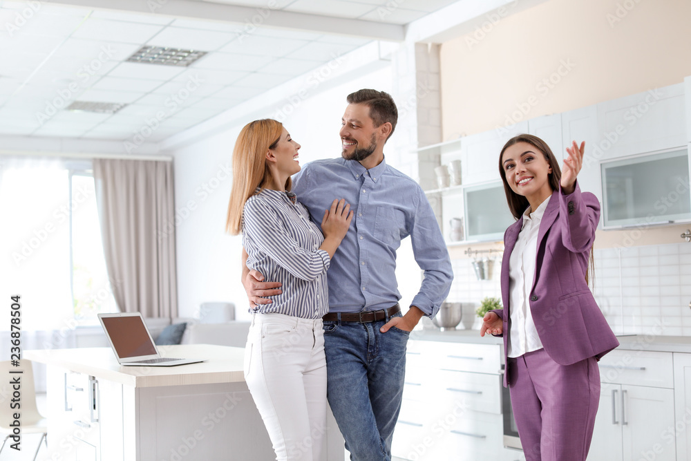 Female real estate agent showing new house to couple, indoors Female real estate agent showing new house to couple, indoors