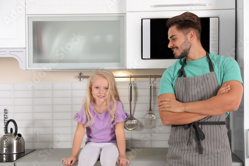 Young man and his daughter near microwave oven in kitchen
