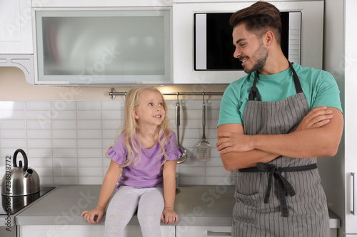 Young man and his daughter near microwave oven in kitchen