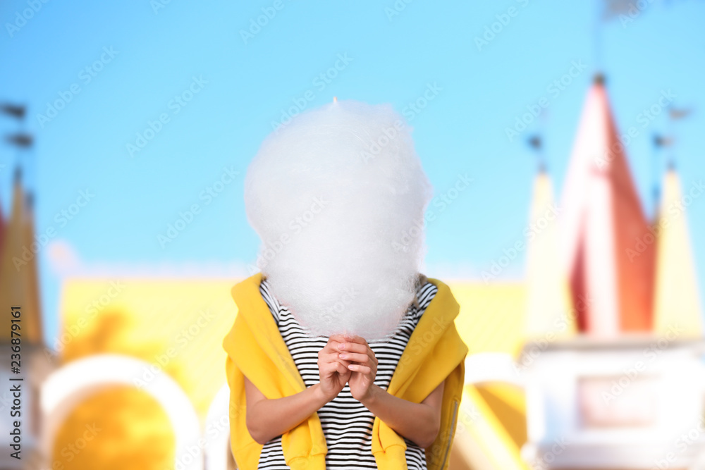 Young woman having fun with cotton candy in amusement park