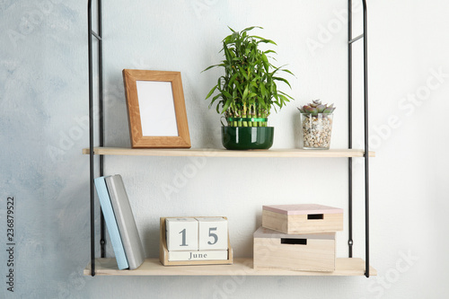 Shelves with green lucky bamboo in pot and decor on light wall