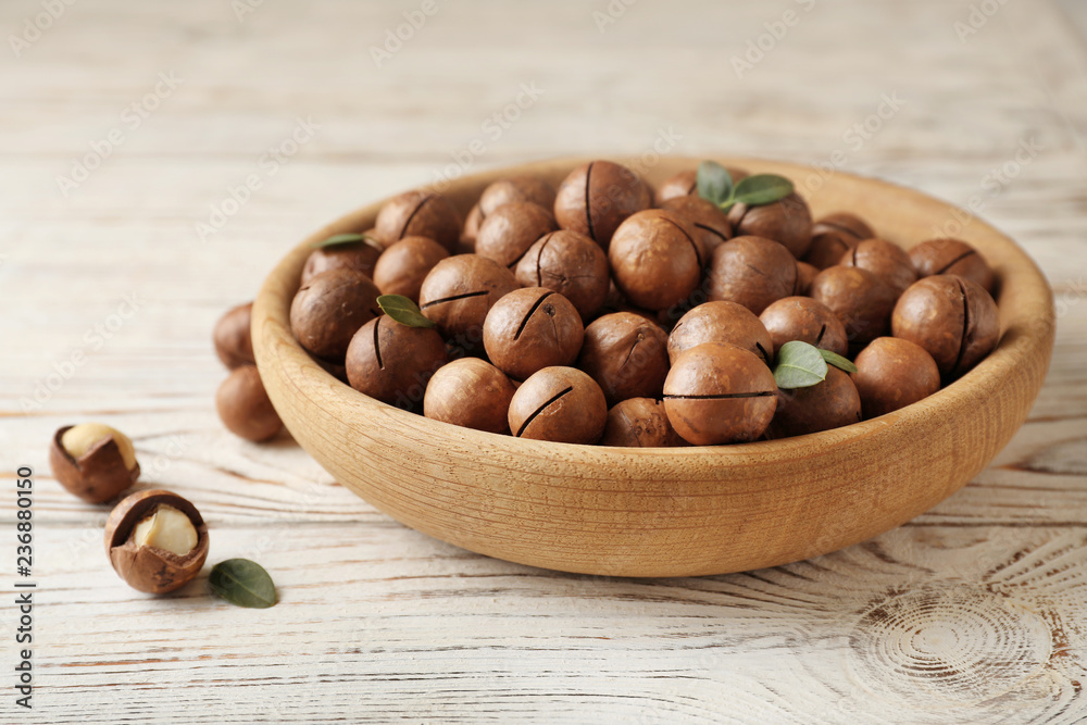 Plate with organic Macadamia nuts on wooden background Plate with organic Macadamia nuts on wooden background