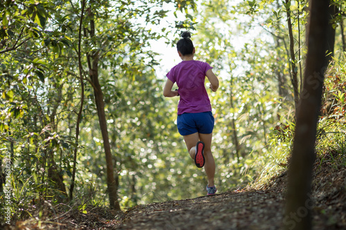 Woman trail runner running in forest mountain