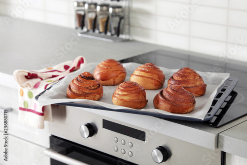 Tray with freshly oven baked buns on stove in kitchen