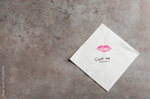 Paper napkin with lipstick mark, words CALL ME and space for text on grey background, top view