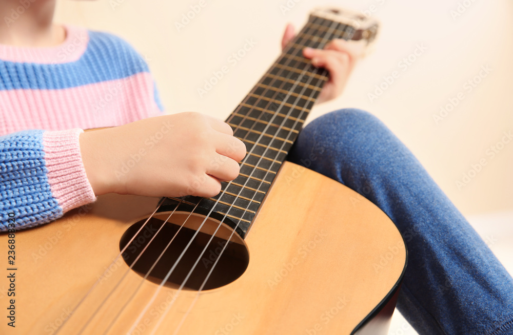 Fototapeta premium Little girl playing wooden guitar, closeup view