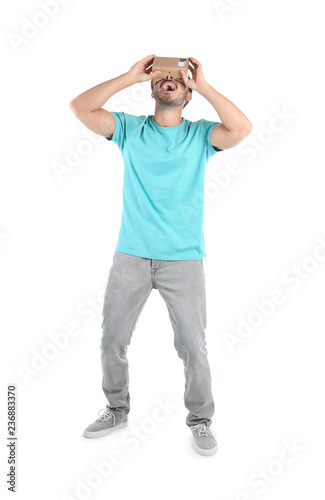 Young man using cardboard virtual reality headset, isolated on white