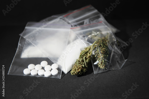 Cocaine, dried hemp and ecstasy on grey table