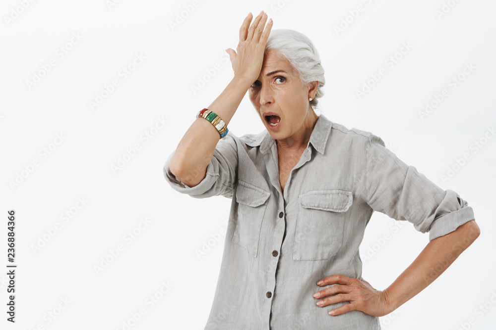 Old lady being shocked with how dumb teenagers are. Portrait of amazed and irritated senior woman with white hair punching forehead and opening mouth feeling astonished seeing stupid actions of kids Old lady being shocked with how dumb teenagers are. Portrait of amazed and irritated senior woman with white hair punching forehead and opening mouth feeling astonished seeing stupid actions of kids
