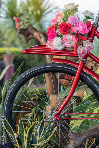 Beautiful artificial flowers on a red antique bike.