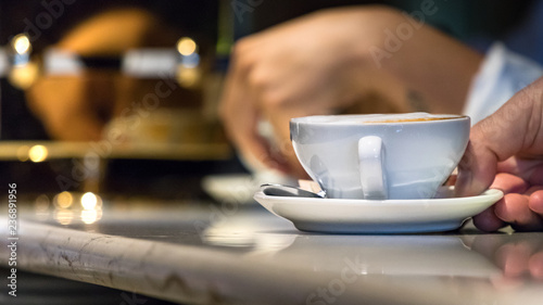 Man waiter hand serving on the counter a cappuccino cup in a coffee shop, Italy.