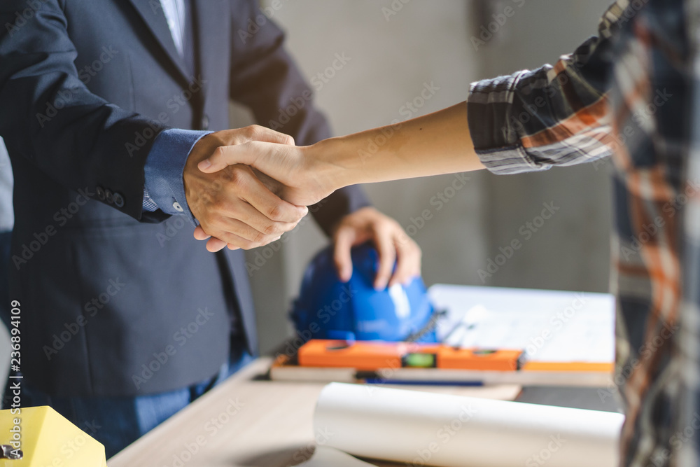 construction worker and contractor. Client shaking hands with team builder in renovation site.