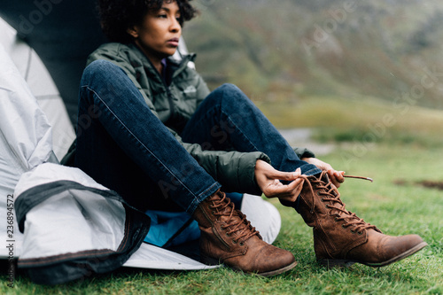 Woman tying her shoelaces by her tent photo