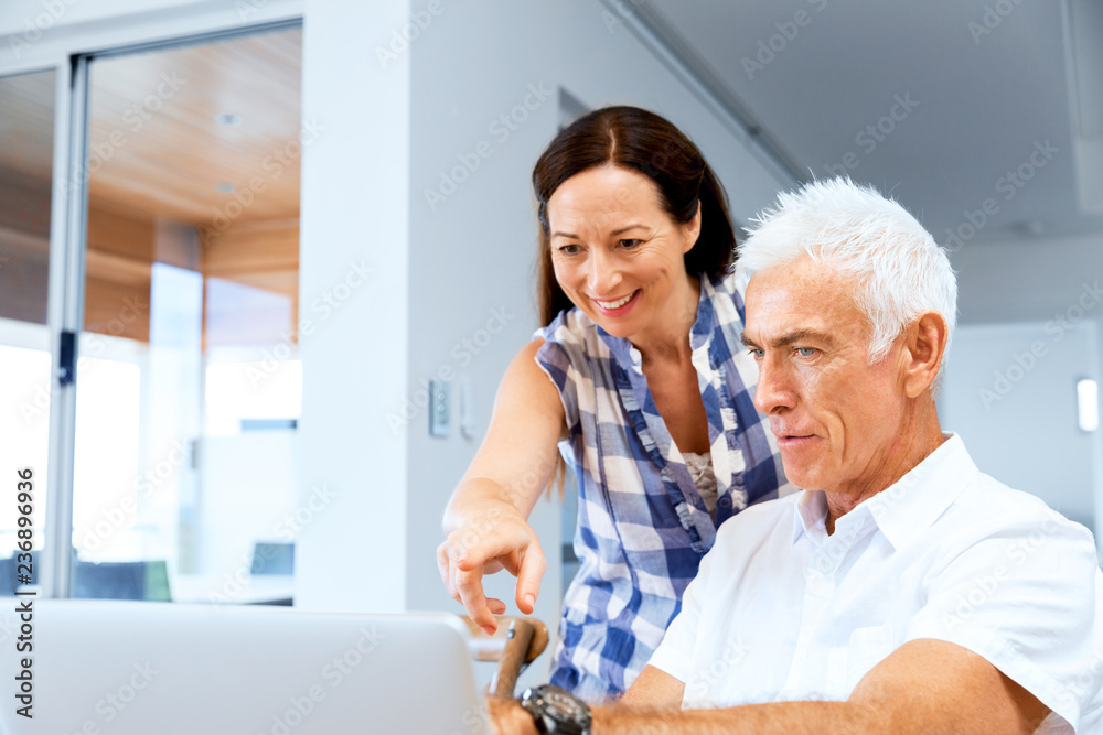 Happy modern mature couple working on laptop at home Happy modern mature couple working on laptop at home