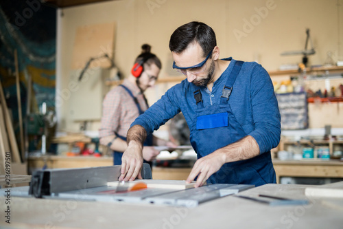 Waist up portrait of mature carpenter working with wood in joinery, copy space