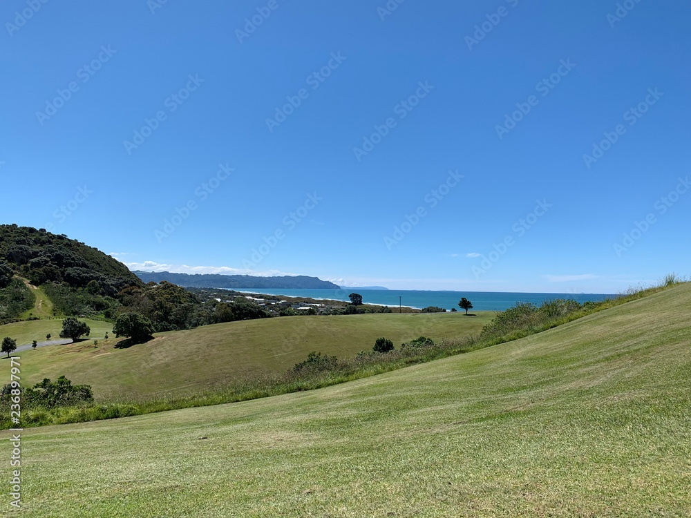 Rolling hills in the foreground with clear blue sea and sky in the background 