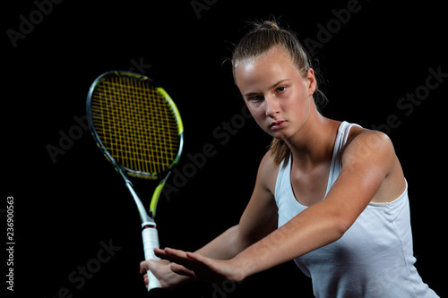 Portrait of beautiful woman playing tennis indoor. Isolated on black. © FS-Stock