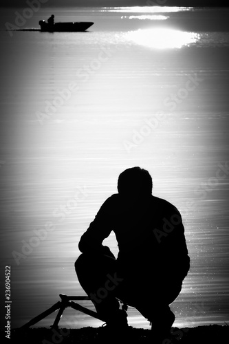 Silhouette man take a photo near lakeside at sunset. Iznik(Nicaea), Bursa, Turkey. Black and white artwork. photo