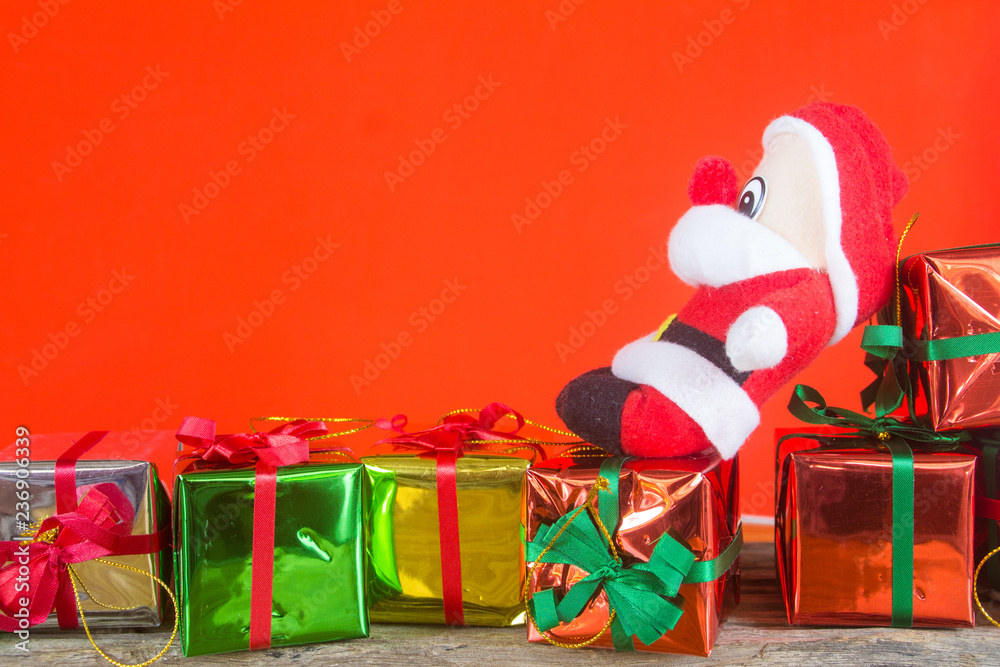 gift box and santa claus doll on the wooden table with red background
