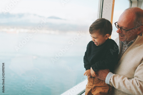 Grandfather and grandson laughing and looking out the window. 