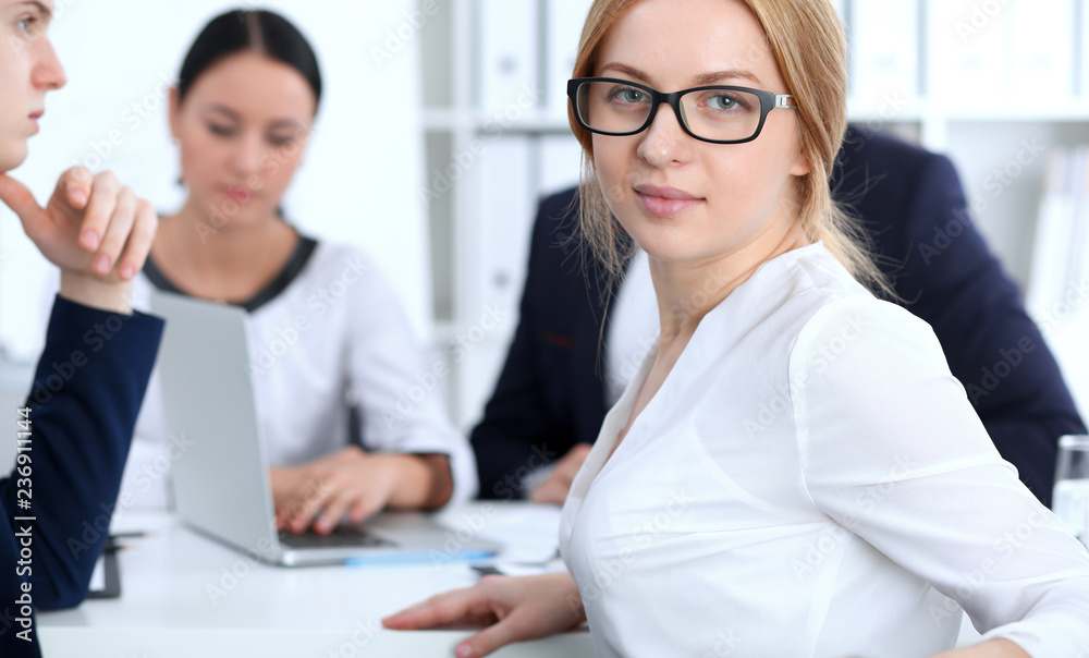 Business People group at meeting in office. Focus at beautiful cheerful smiling businesswoman. Conference, corporate training or brainstorming of team. Success and negotiation concept Business People group at meeting in office. Focus at beautiful cheerful smiling businesswoman. Conference, corporate training or brainstorming of team. Success and negotiation concept