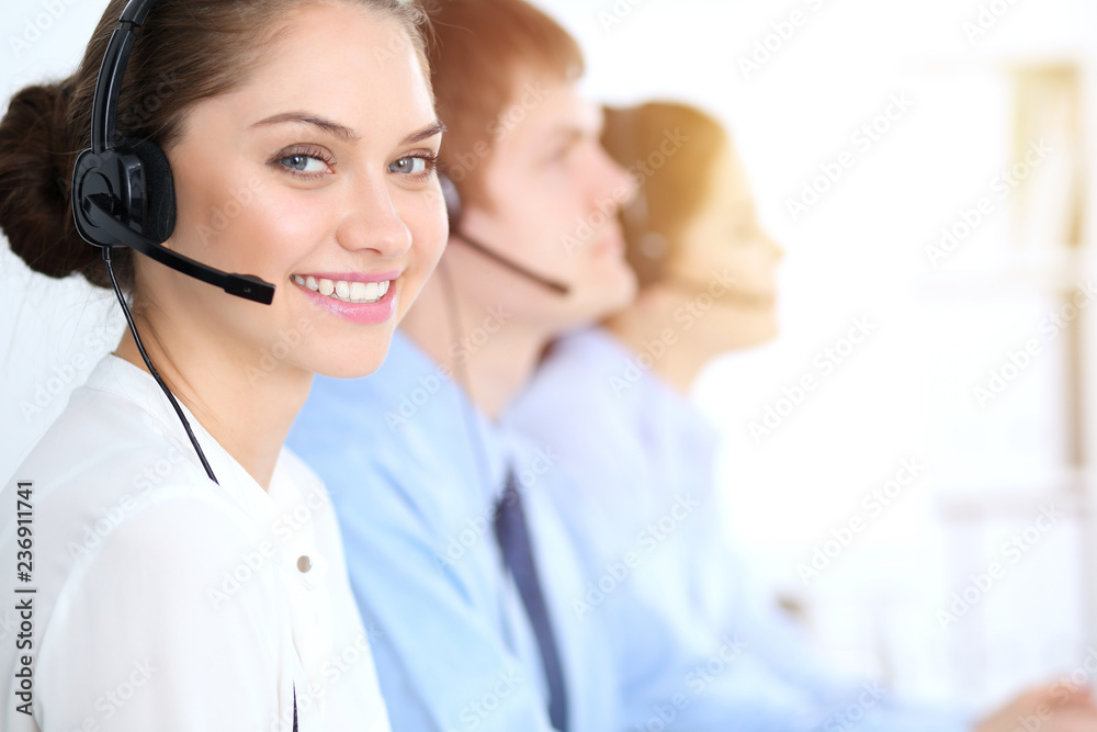 Call center operators at work. Focus at business woman in headset Call center operators at work. Focus at business woman in headset