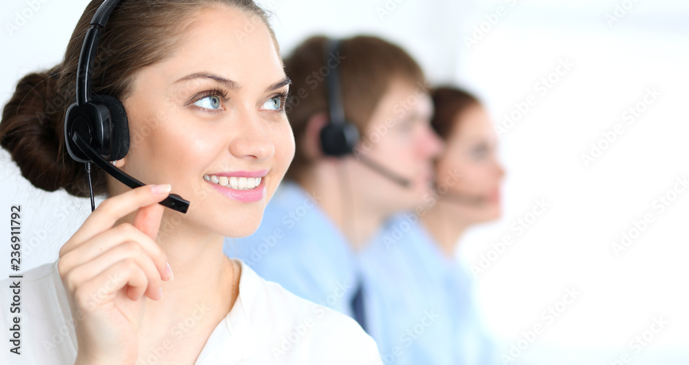 Call center operators at work. Focus at business woman in headset Call center operators at work. Focus at business woman in headset